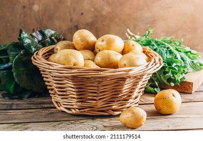 Fresh raw baby potato in a basket over wooden background. - Shutterstock ID 2111179514