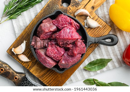 Fresh raw beef cubes set, on white stone surface, top view flat lay