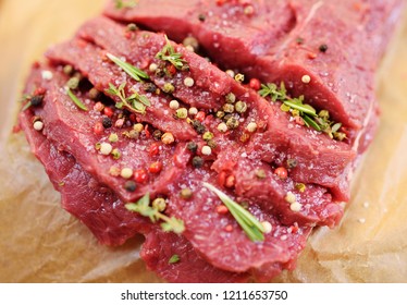 Fresh raw beef meat close-up with seasonings - peppers, rosemary,salt. Preparation for grilling. 