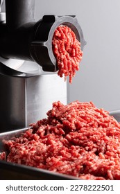 the fresh raw beef meat in the grinder The meat industry the process of cooking minced  at home  the meat is put in the  grinder and minced comes out of it.