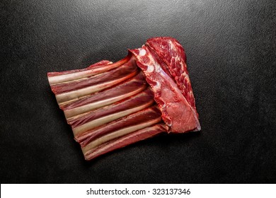 Fresh raw beef spare ribs. Uncooked mutton rack of beef. Piece of meat with bones on black ceramic