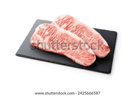Fresh raw beef steak placed on a stone plate against a white background. Wagyu beef steak.