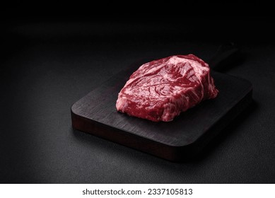 Fresh, raw beef steak with salt, spices and herbs on a dark textured background - Shutterstock ID 2337105813