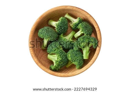 Fresh raw broccoli florets in a wooden bowl isolated on white background, top view.