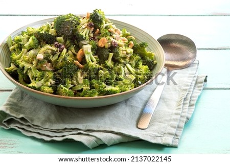 Fresh raw broccoli salad with spring onion, peanuts and dried blueberries with vinaigrette salad dressing 
