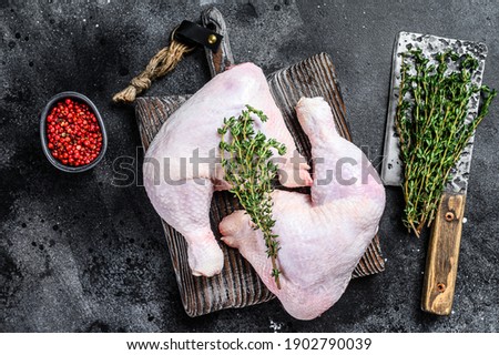 Fresh raw chicken legs on a cutting board. Black background. Top view.