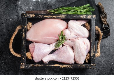 Fresh raw chicken meat and chicken parts - drumstick, breast fillet, wing, thigh. Black background. Top view