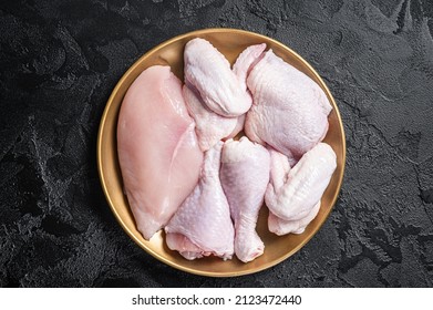 Fresh raw chicken meat with various parts - drumstick, breast fillet, wings, thigh. Black background. Top view