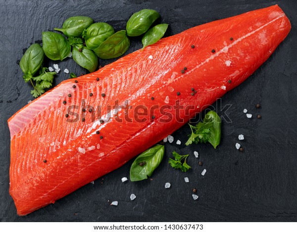 Fresh raw copper river sockeye salmon\
fillet on natural stone with herbs and seasoning \
