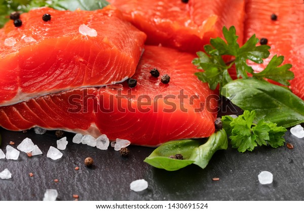 Fresh raw copper river sockeye salmon\
fillets on natural stone with herbs and seasoning \

