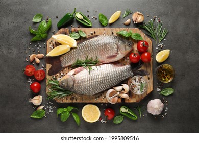 Fresh raw crucian carps and ingredients on grey table, flat lay. River fish