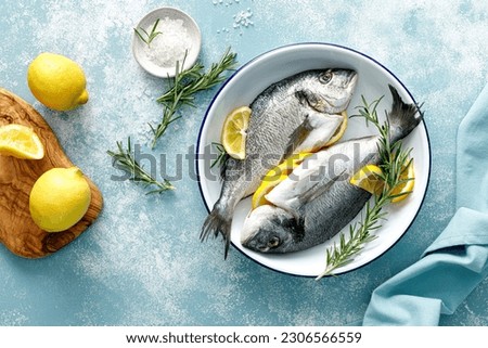 Fresh raw dorado fish cooking with lemon and rosemary. Sea bream, dorado. Seafood, healthy food. Top view