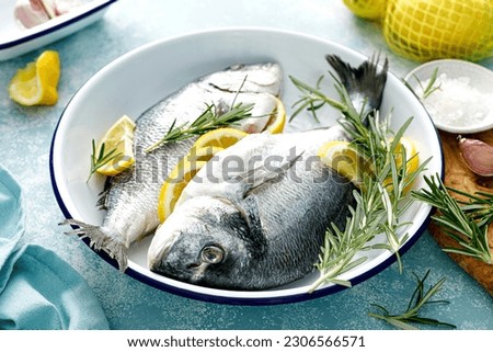 Fresh raw dorado fish cooking with lemon and rosemary. Sea bream, dorado. Seafood, healthy food