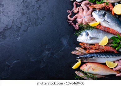 Fresh Raw Fish And Seafood Assortment On Black Slate Background. Top View. Copy Space.