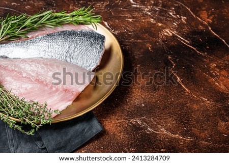 Fresh Raw Gilthead Sea bream fish fillets ready for cooking. Dark background. Top view. Copy space.
