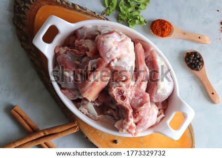 Fresh raw goat meat or mutton or lamb pieces. Preparation for Indian mutton curry. Spice at the background such as cinnamon sticks, red chili powder, black pepper & coriander. Copy space.