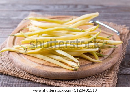 Fresh raw green beans on a cutting board on a wooden table