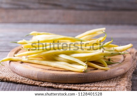 Fresh raw green beans on a cutting board on a wooden table