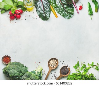 Fresh raw greens, unprocessed vegetables and grains over light grey marble kitchen countertop, top view, copy space. Clean eating, healthy, vegan, vegetarian, detox, dieting food concept