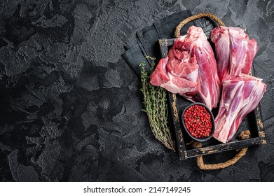 Fresh Raw lamb shanks with herbs and spices, mutton meat. Black background. Top view. Copy space.