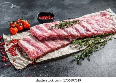 Fresh raw lamb spare ribs with spices and herbs. Black background. Top view