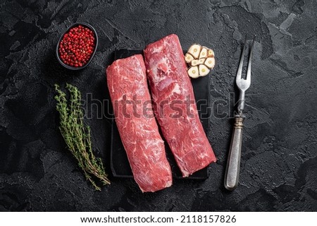 Fresh Raw lamb tenderloin, Mutton loin fillet Meat on marble board. Black background. Top view