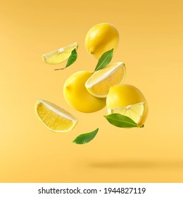 Fresh raw lemons with green leaves falling in the air isolated on yellow illuminating background. Food levitation or zero gravity conception. High resolution image - Shutterstock ID 1944827119