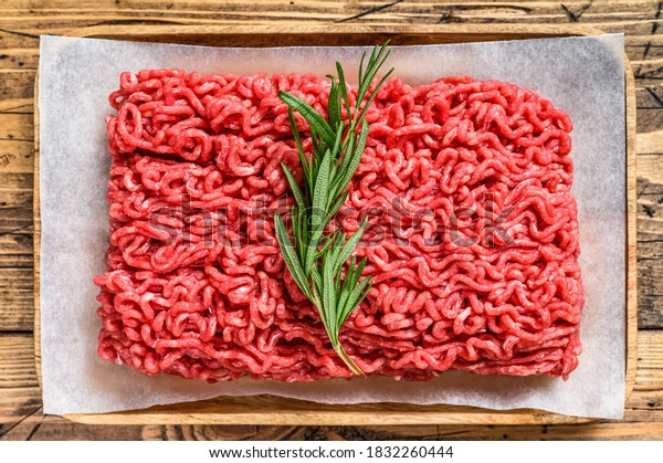 Fresh Raw mince beef, ground meat on butcher\
paper. wooden background. Top\
view