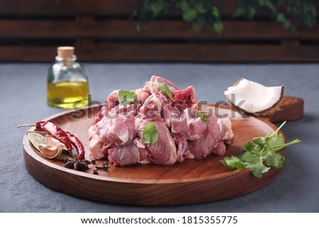 Fresh raw mutton pieces cut for biriyani with spices on grey stone background