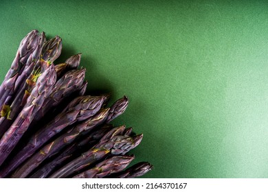 Fresh raw organic asparagus bunch, purple, green and white vegetable on dark green background 
