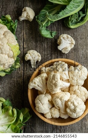 Fresh raw organic cauliflower with leaves on rustic background, uncooked vegetable