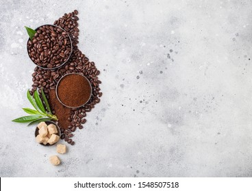 Fresh Raw Organic Coffee Beans With Ground Powder And Cane Sugar Cubes With Coffee Trea Leaf On Light Kitchen Table. Space For Text