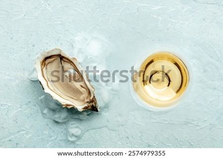 Fresh raw oyster with a glass of wine, on ice, on a slate background, overhead flat lay shot