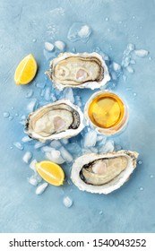 Fresh raw oysters, overhead shot on ice with a glass of white wine and lemon slices