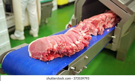 Fresh Raw Pork Chops In Meat Factory. Raw Meat Cuts On A Industrial Conveyor Belt. 
Meat Processing In Food Industry. Industrial Food Processing Machine Cutting Pork Chops.