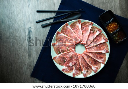 fresh raw pork, meat ,beef, belly, sliced on square dish disk plate  on fabric and wood, wooden background, shabu, hot pot ingredients.