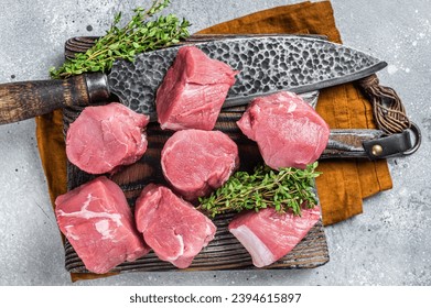 Fresh Raw pork tenderloin medallions steaks on a wooden cutting board. Gray background. Top view.
