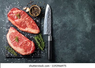 Fresh Raw Prime Black Angus Beef Steaks On Stone Board: Striploin, Rib Eye. Top View With Copy Space. On A Dark Background