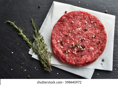 Fresh Raw Prime Black Angus Beef Burger Patty On Black Stone Background. Top View.