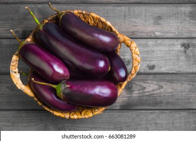 Fresh raw Purple Eggplant in a special wicker basket for Eggplant on gray wooden background. Top view, blank space.