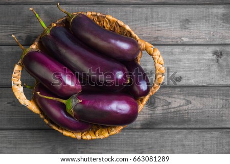 Fresh raw Purple Eggplant in a special wicker basket for Eggplant on gray wooden background. Top view, blank space.