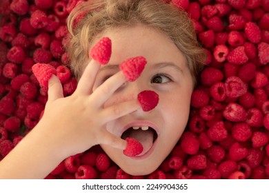 Fresh raw raspberry near kids face. Raspberri macro. Top view of collection raspberries. Kid holding raspberries on her fingers. Raspberries background.
