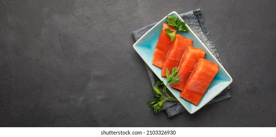 Fresh Raw Red Salmon Fish Fillet With Herbs. Black Stone Background. Top View. Cooking Concept.