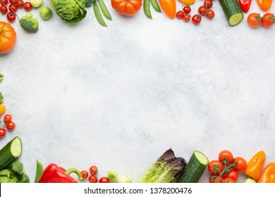 Fresh raw salad ingredients, vegetables tomatoes cucumbers lettuce pepper spring onion broccoli peas on the white table, top view, copy space, selective focus