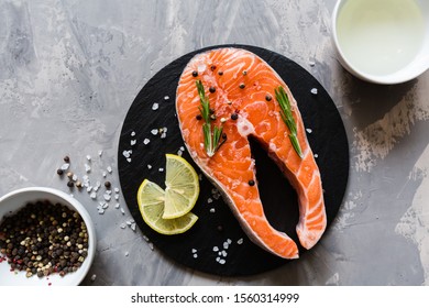 Fresh Raw Salmon Fish Steak With Spices On Dark Stone Background. Creative Layout Made Of Fish, Top View, Flat Lay, Mockup, Overhead. Healthy Food Concept