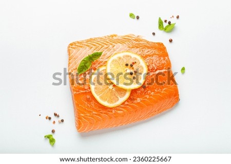 Fresh raw salmon marbled fillet isolated on white background with lemon, coarse salt, green herbs top view. Healthy nutrition and balanced diet