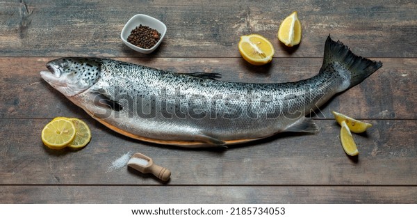 Fresh\
raw salmon, red fish with spices, salt, lemon, pepper, rosemary on\
dark wooden background. Fresh raw salmon fish with spices, top\
view. Raw fish carcass on wood table\
background.