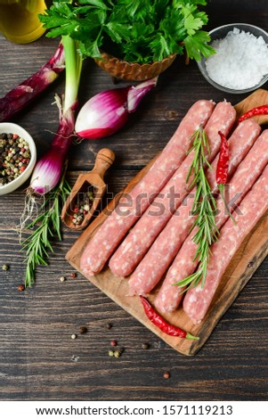 Fresh raw sausages with ingredients for sauce onion parsley spices. Fresh sausages from meat beef or pork or chicken