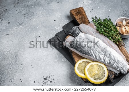 Fresh Raw Sea Bass fillets, Branzino fish with thyme and lemon. Gray background. Top view. Copy space.