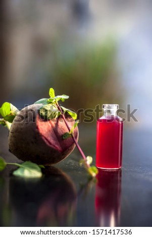 Fresh raw sliced beetroot along with some mint leaves and its extracted essence oil in a tiny glass bottle.Vertical shot with blurred background.